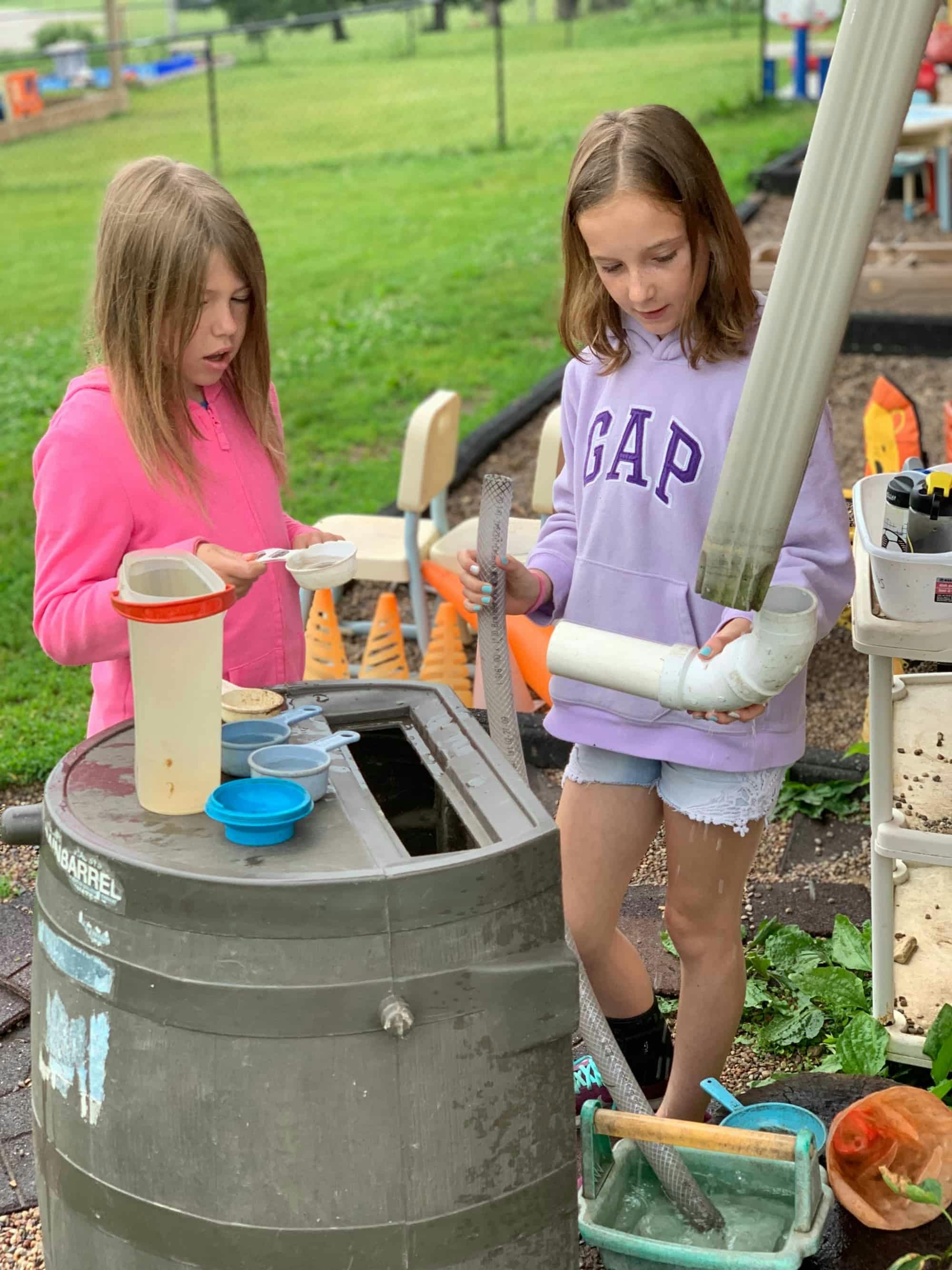 Two children playing with water and pipes outdoors