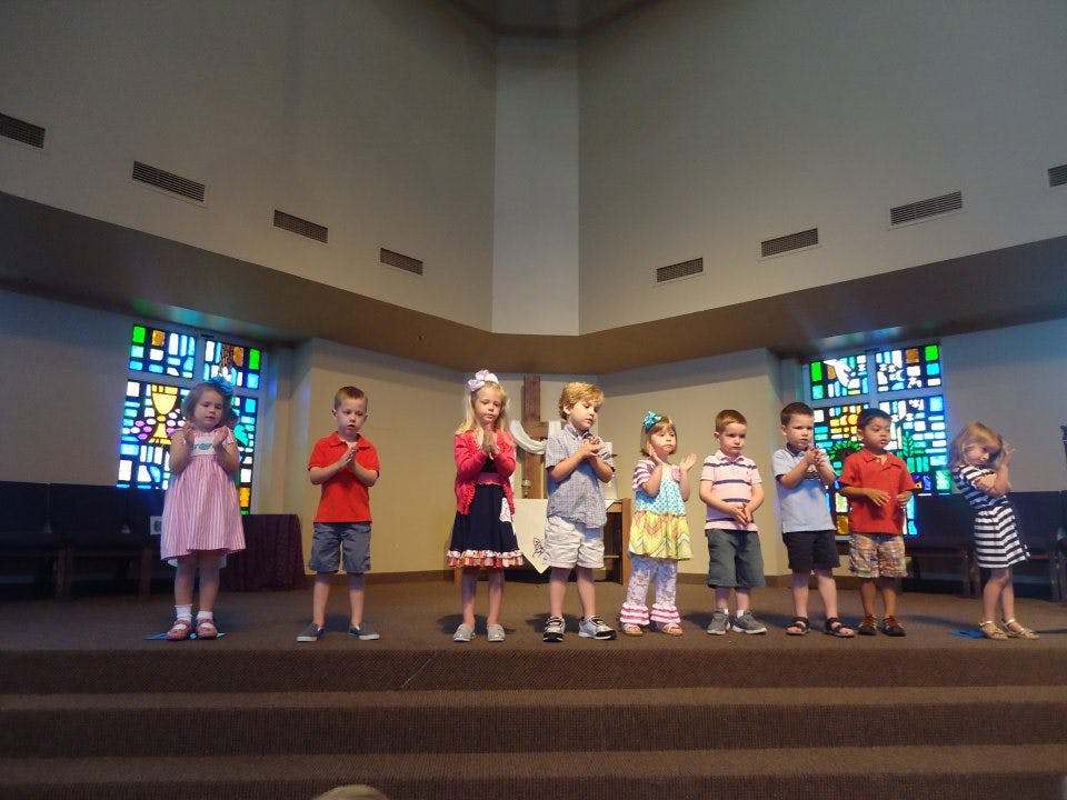Group of children standing on a stage with hands together