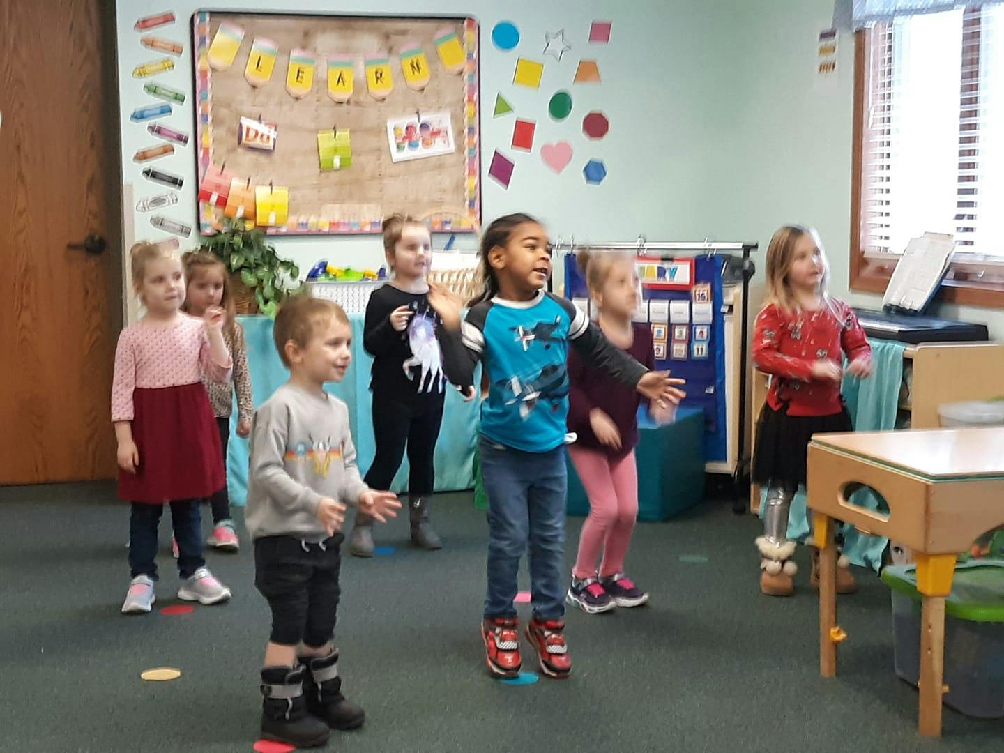 Group of children standing and moving in a classroom