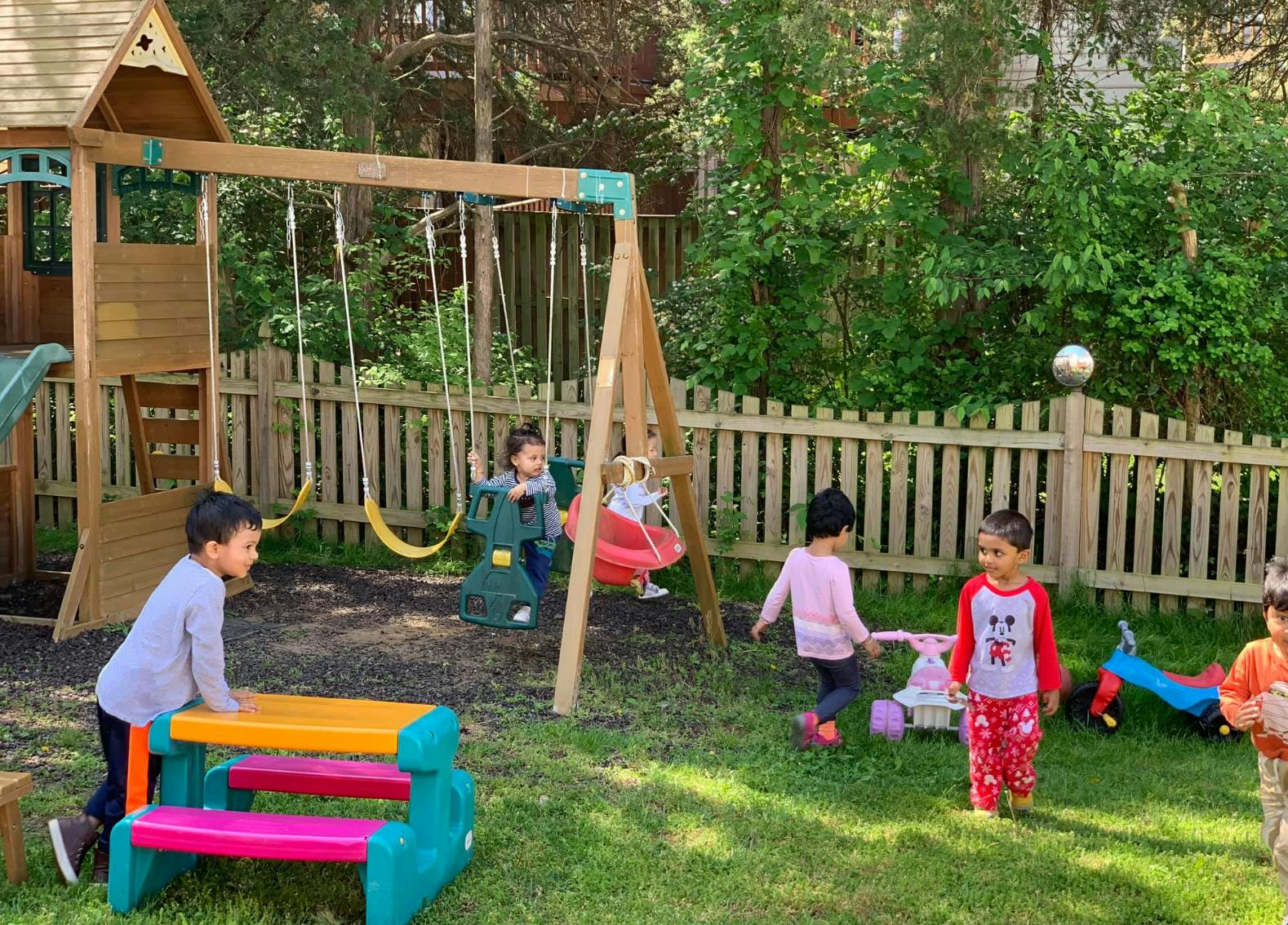 Children playing on a playground with swings and a playhouse