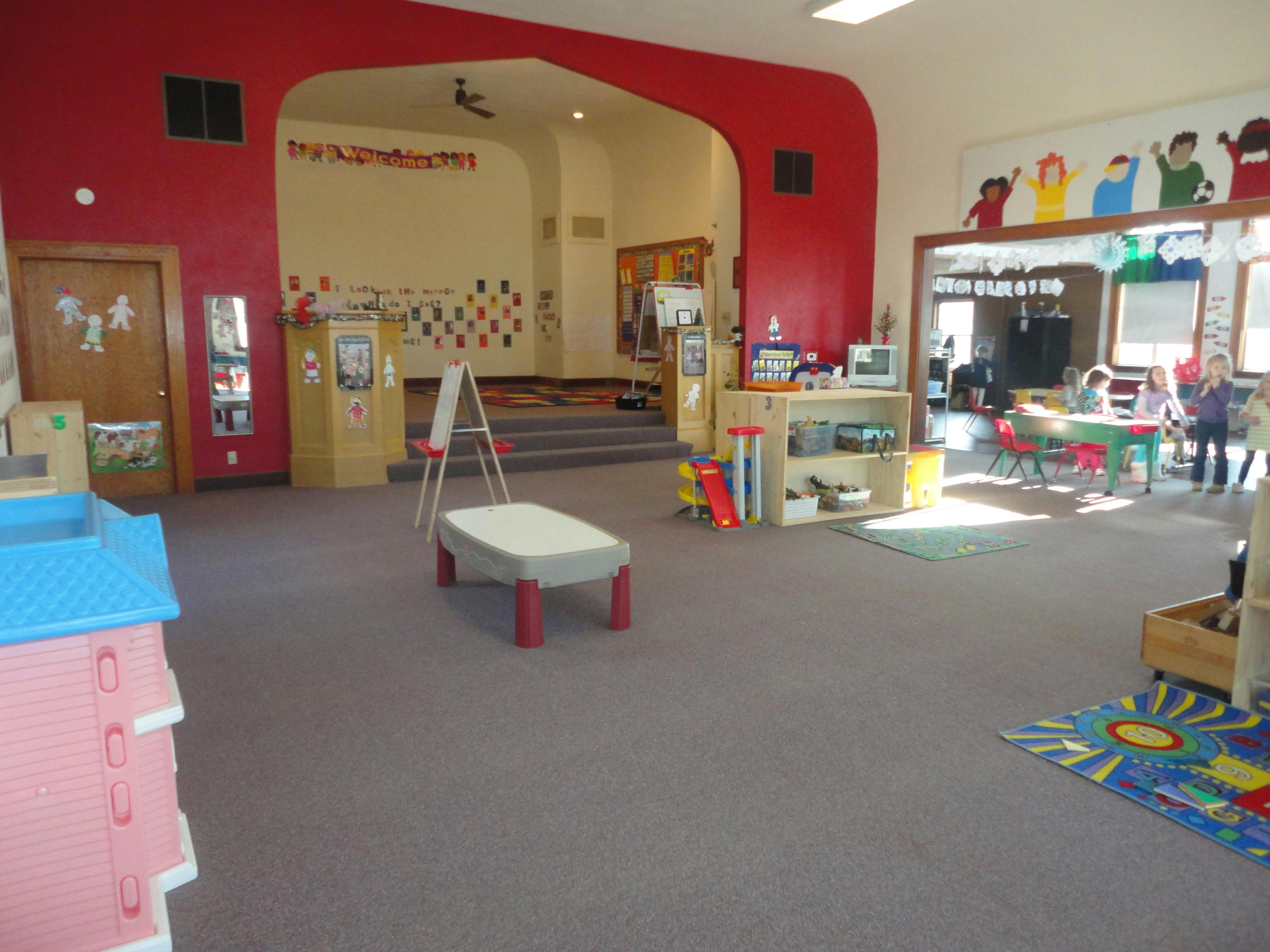 Classroom with red walls and a stage area, children visible in background