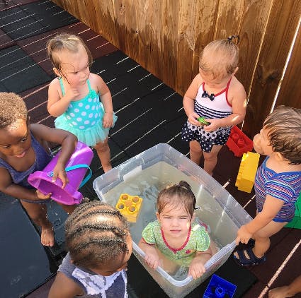 Children playing with water in a plastic bin