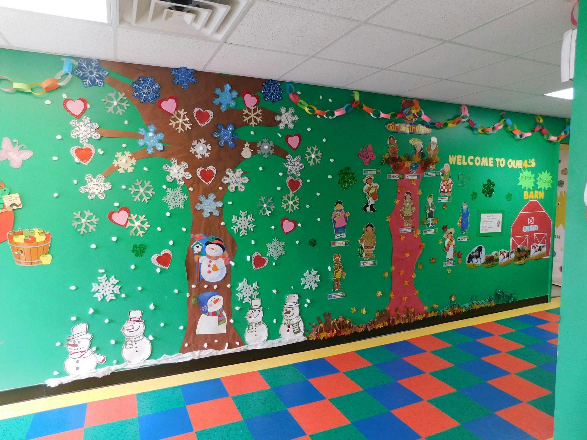Classroom wall decorated with paper trees, snowflakes, snowmen, and hearts