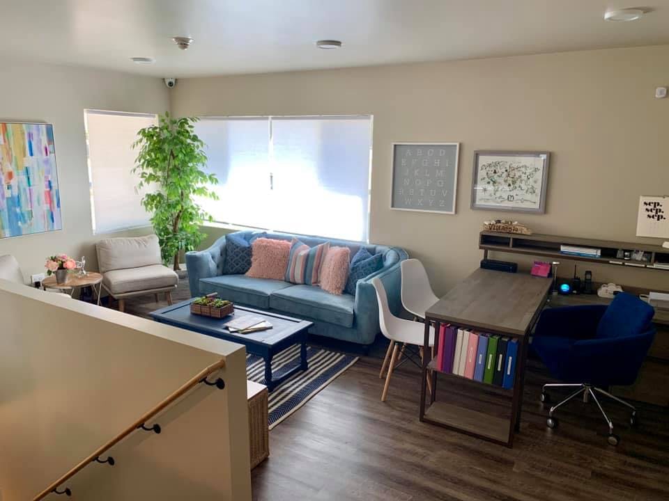 Living room with blue sofa, coffee table, and desk with a desk and chair