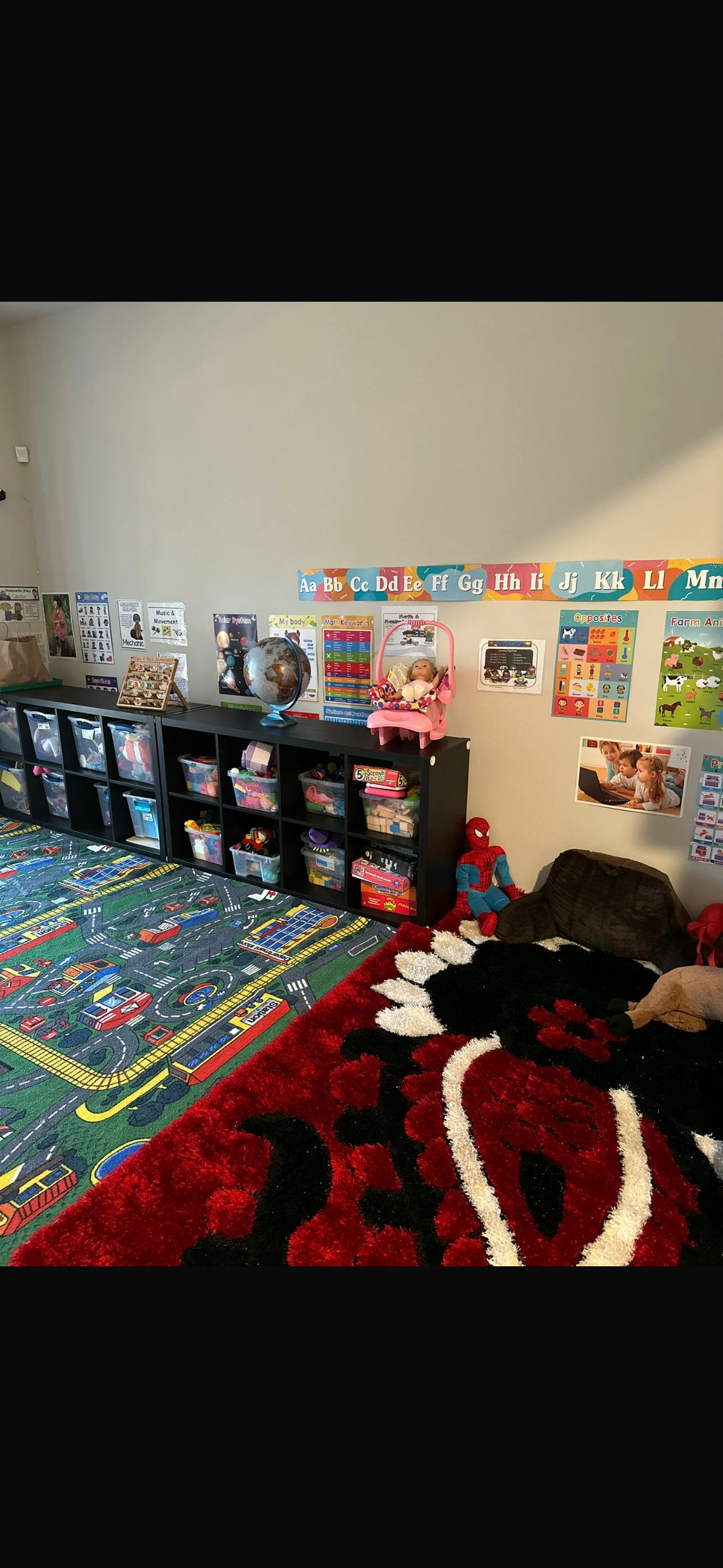 Playroom with shelves of toys, alphabet chart, and two rugs
