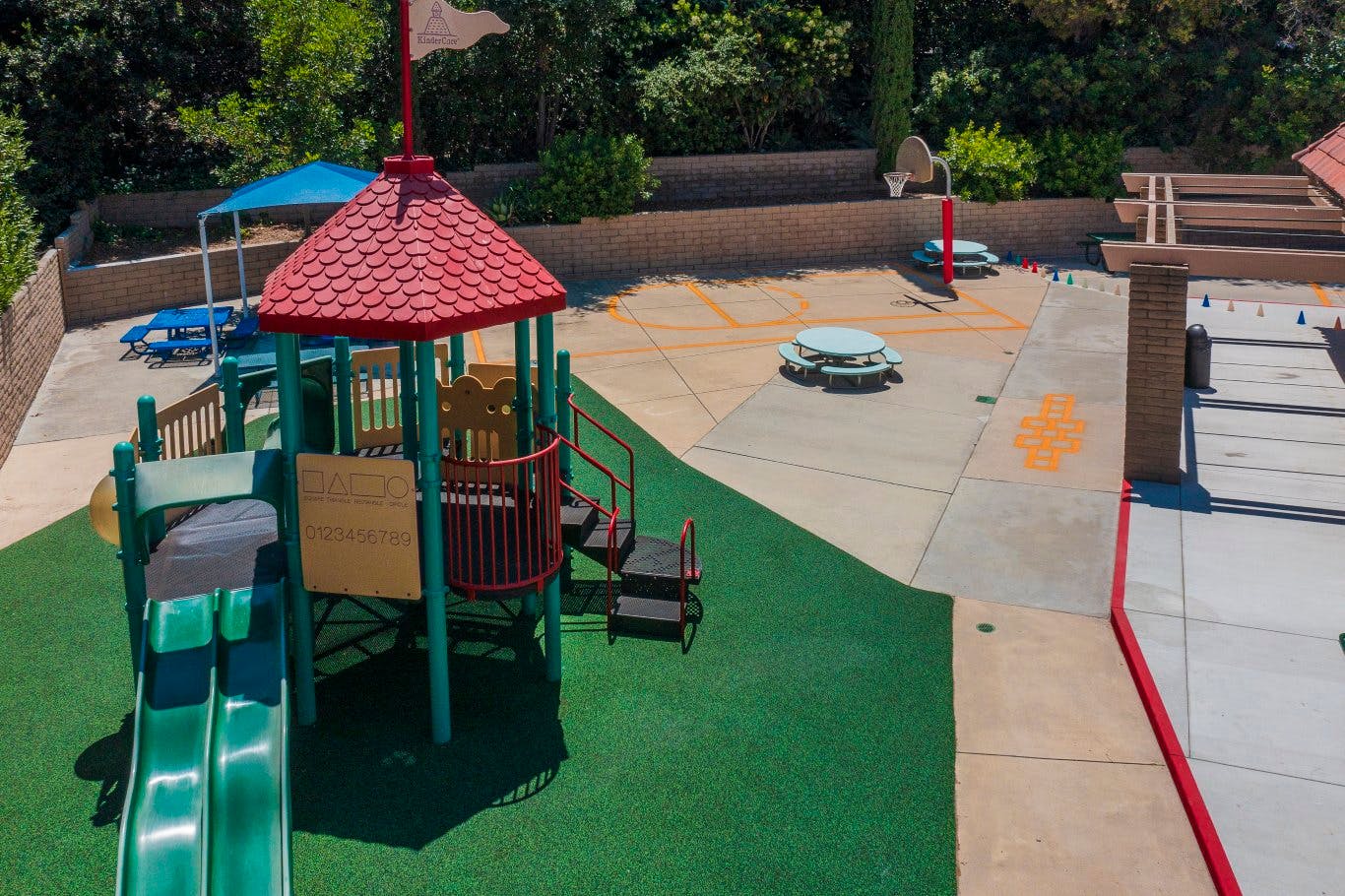 Playground with green turf, red-roofed play structure, and slides