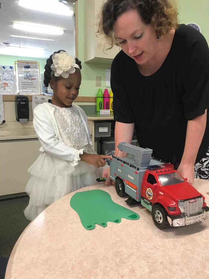 Child and person playing with a toy truck on a table