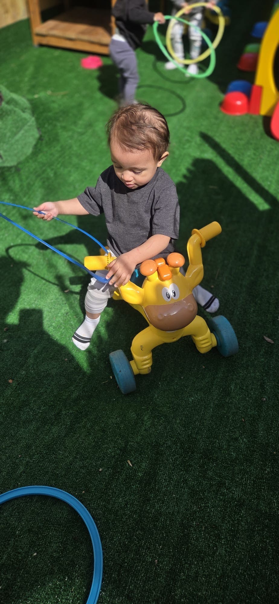 Child playing with a yellow ride-on toy on green turf