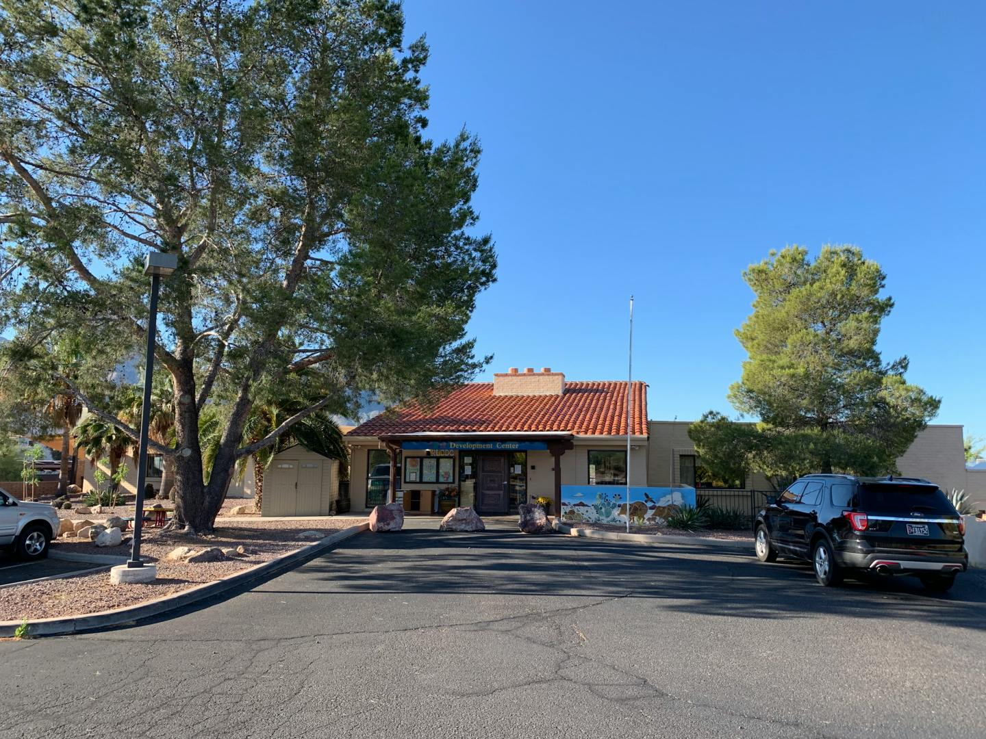 Building with a red tile roof and a black car in a parking lot