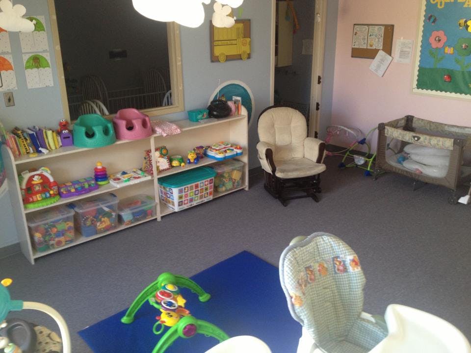 Childcare room with shelves of toys, a crib, and a rocking chair