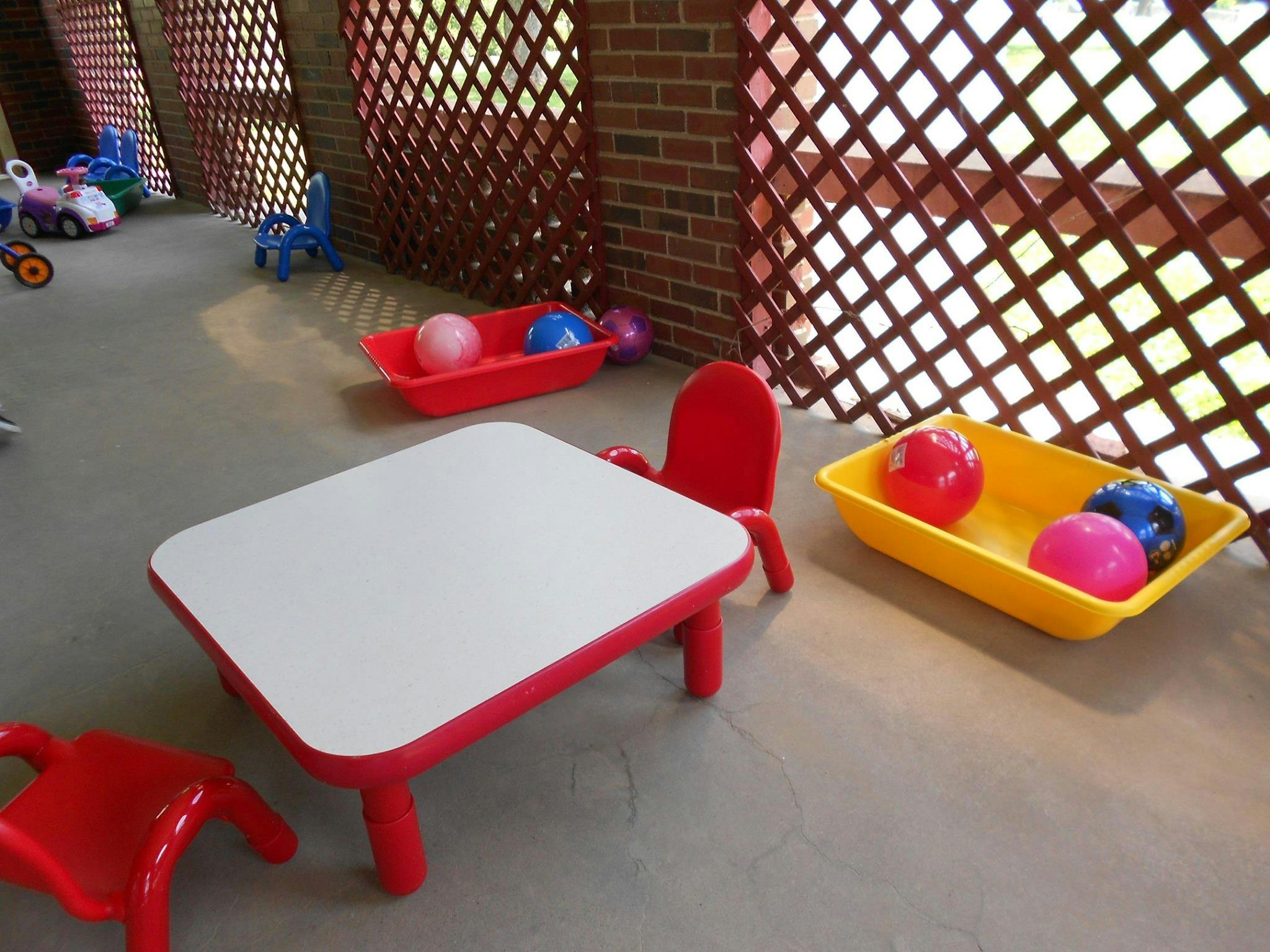 Small red table and chairs with bins of balls in a play area