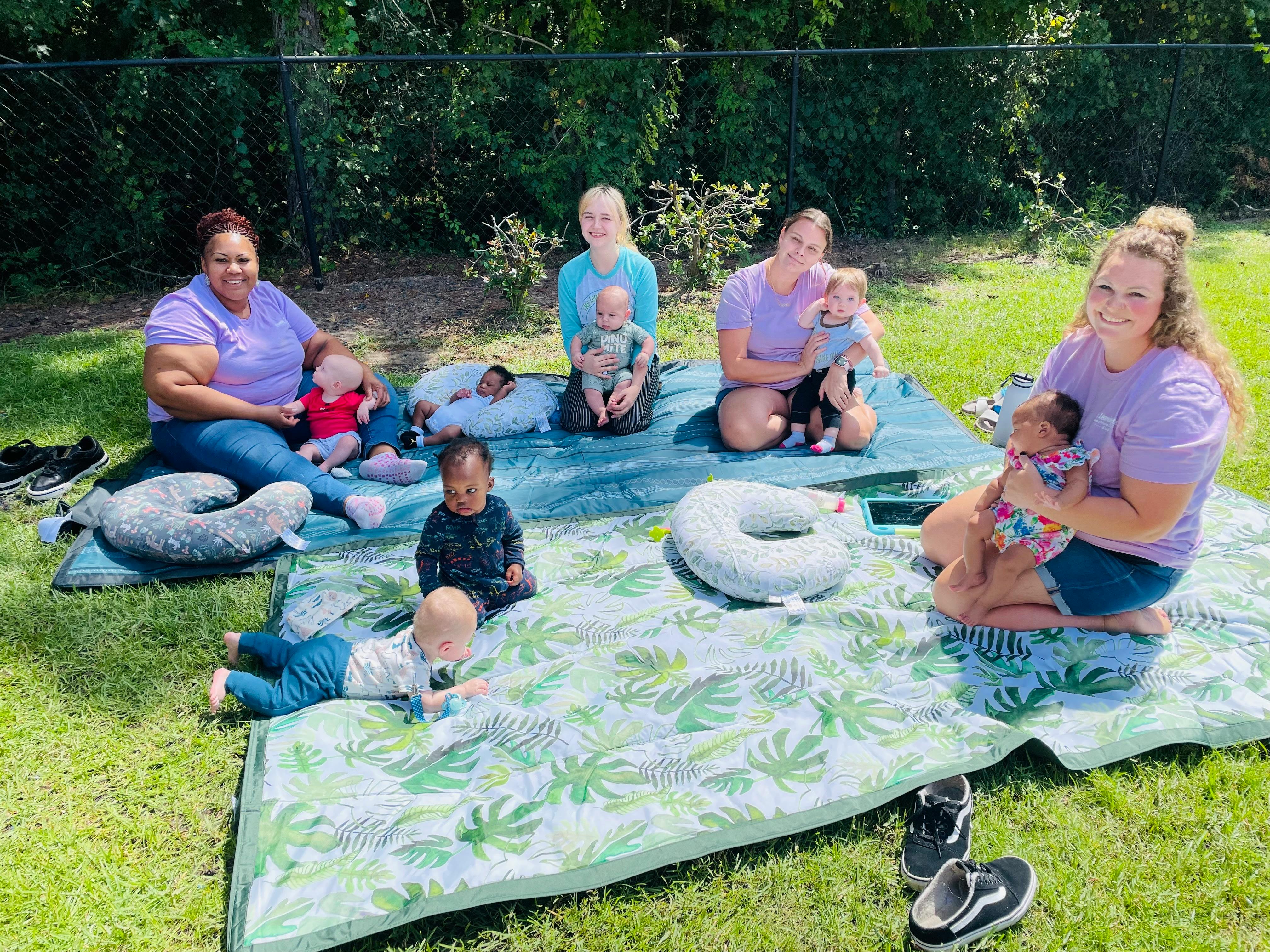 Adults and babies on blankets on grass
