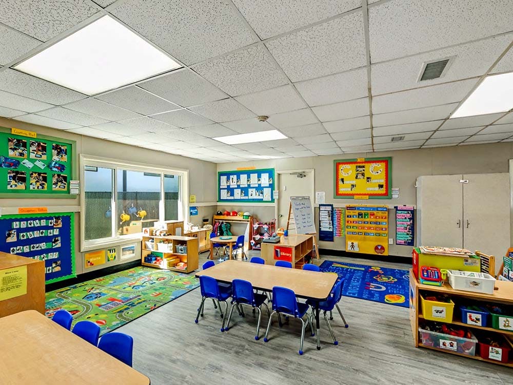 A colorful and organized preschool classroom with small tables and chairs
