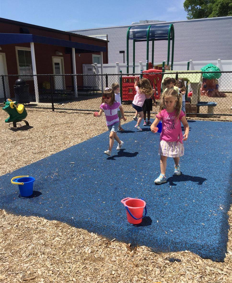 Children playing on a playground with wood chips and blue matting