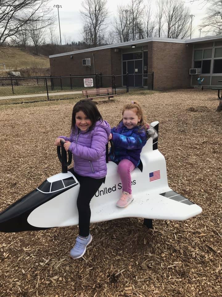 Two children sitting on a space shuttle playground ride