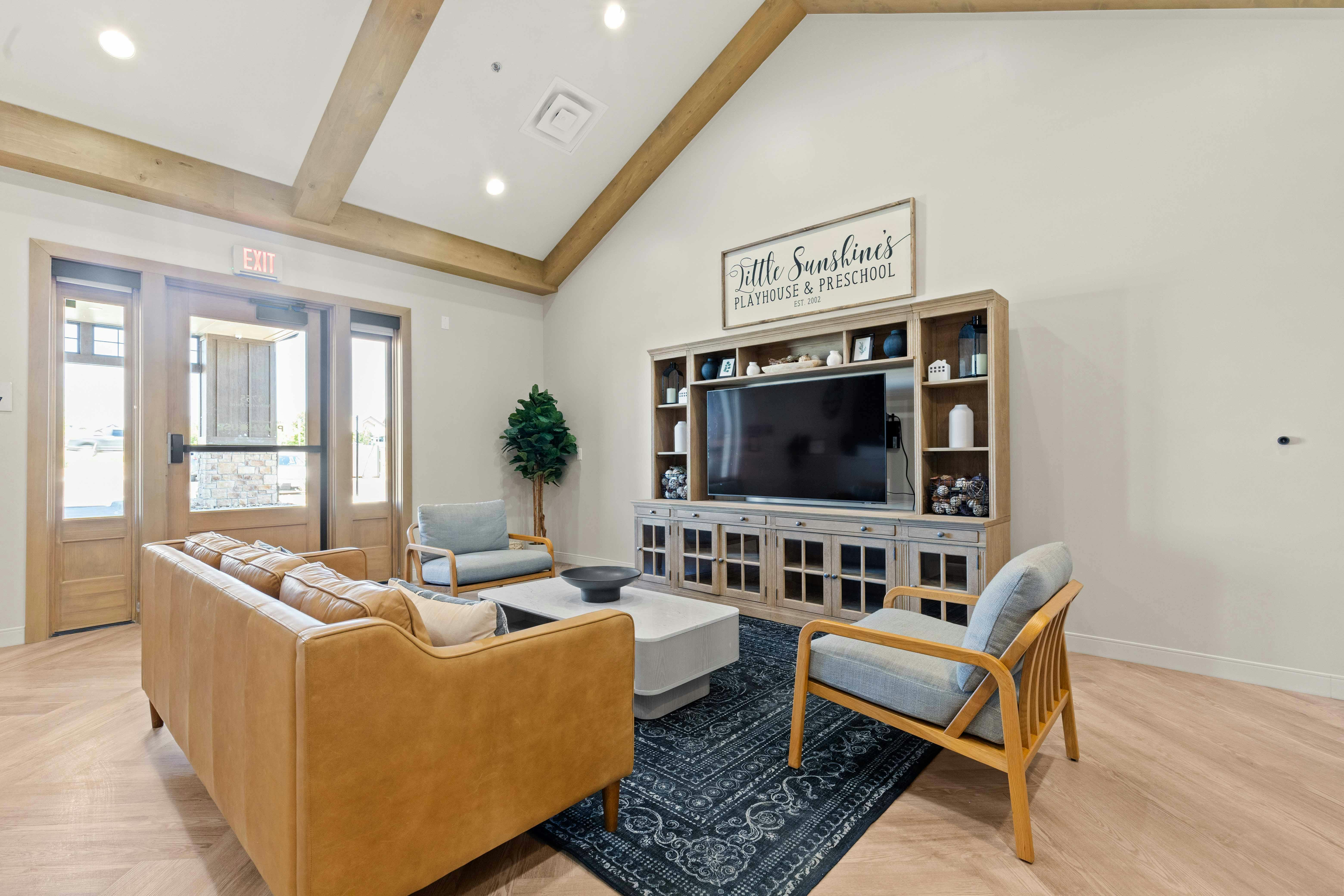 Living room with a brown sofa, two chairs, coffee table, and TV console