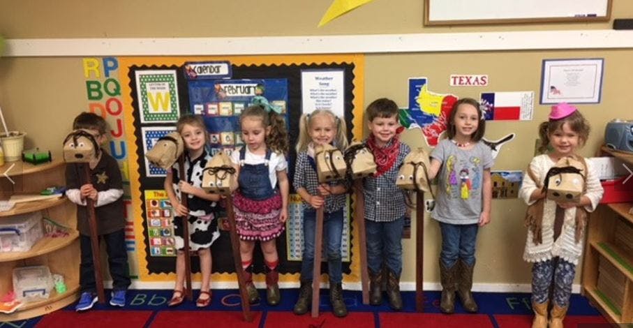 Children holding hobby horses in a classroom