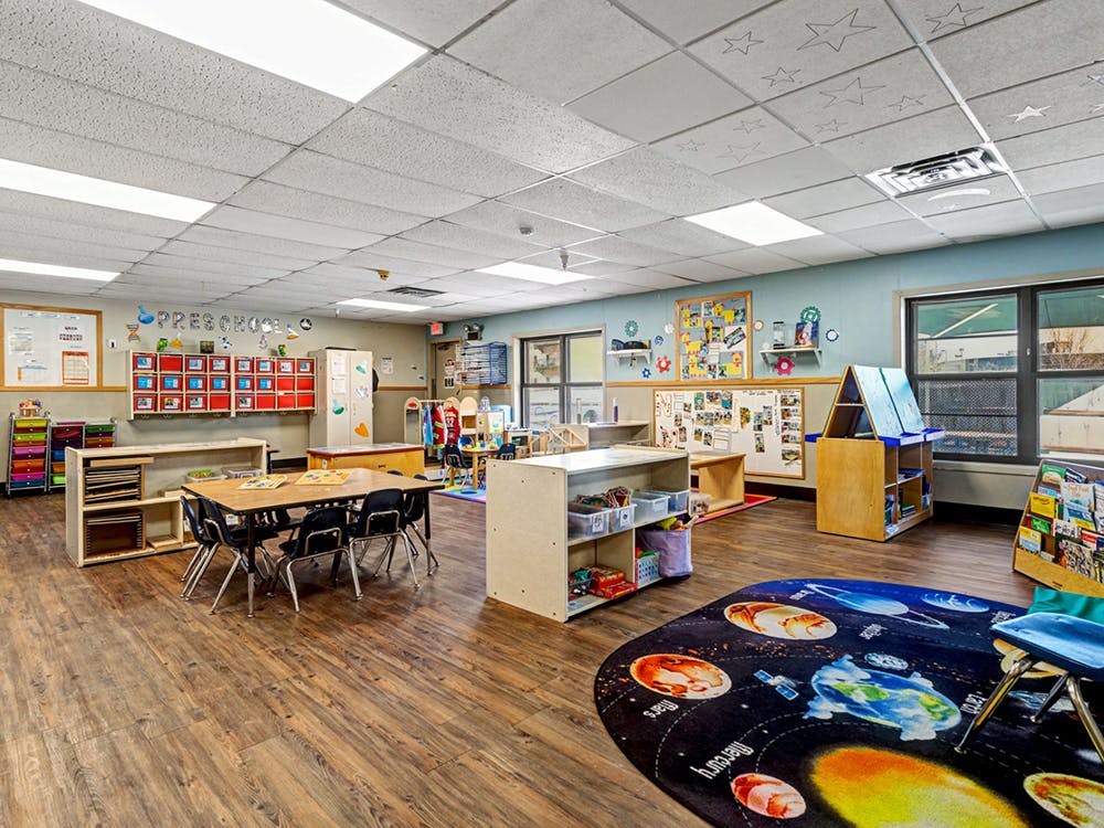 A colorful preschool classroom with tables, chairs, and learning materials