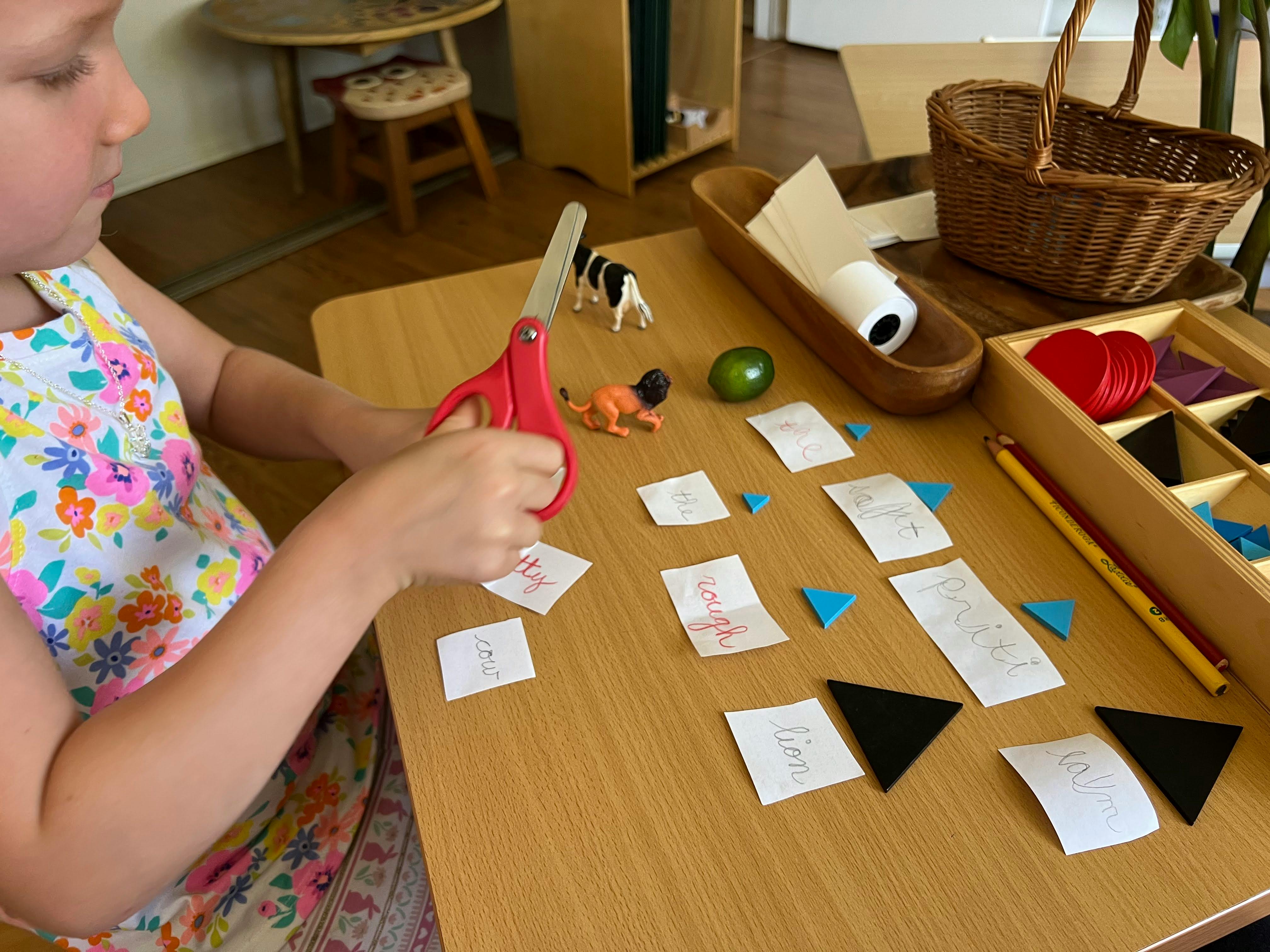 Child cutting paper with red scissors at a table