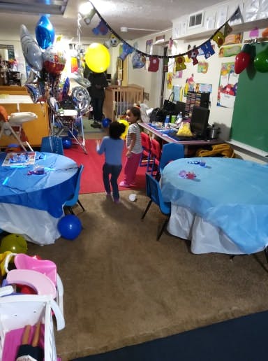 Two children standing in a room with balloons and decorated tables