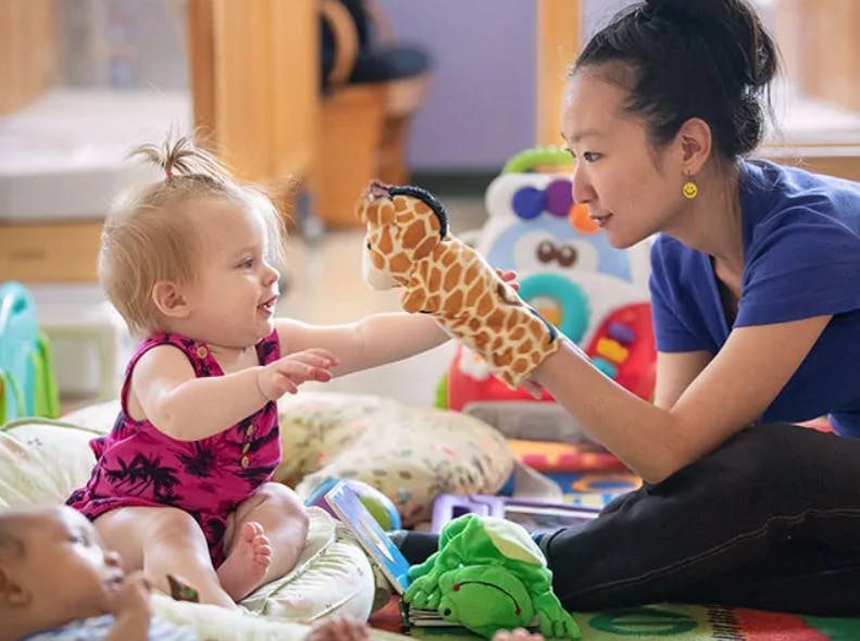 Person holding a giraffe puppet for a child