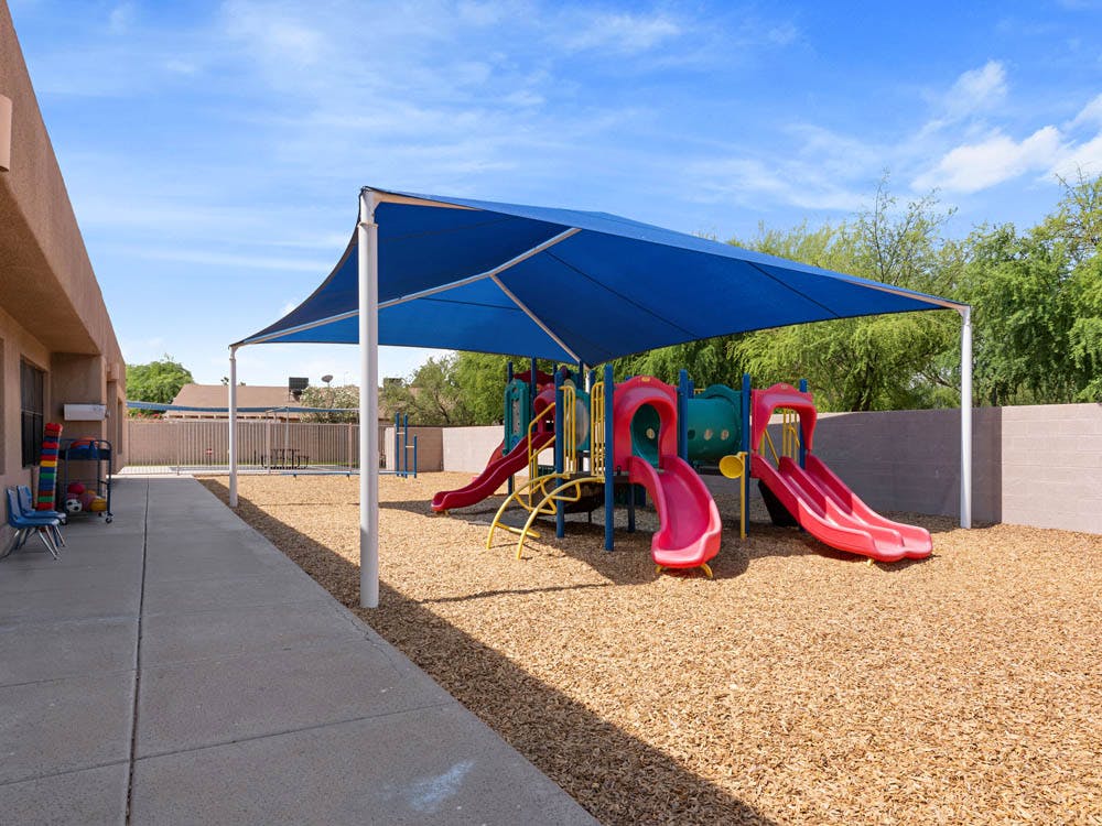 Playground with slides under a large blue shade structure