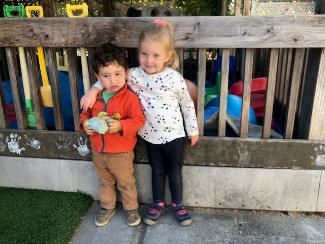Two children standing on a wooden play structure