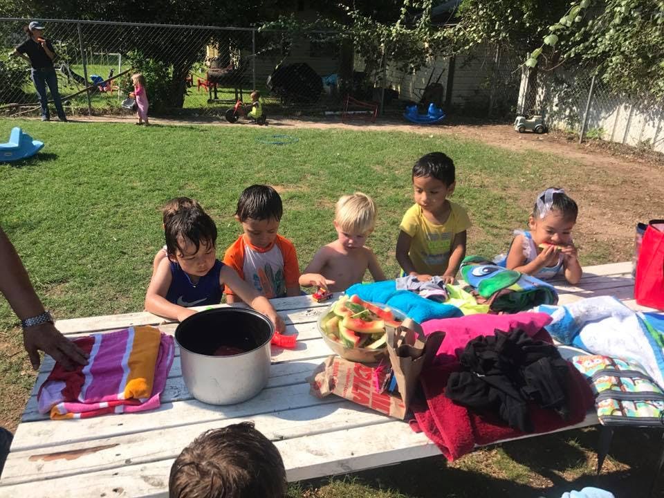 Children playing with items on a picnic table outdoors