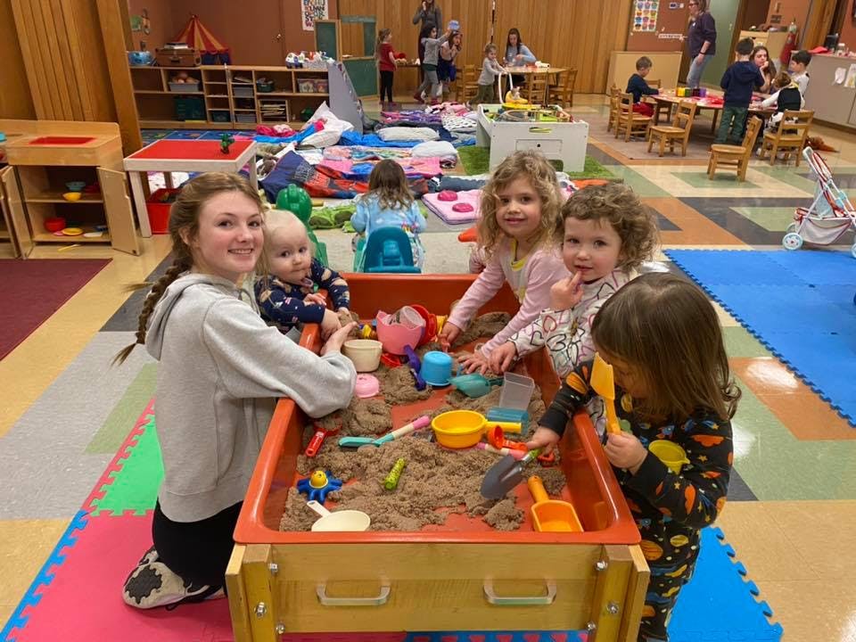 Person and three children playing in a sand table