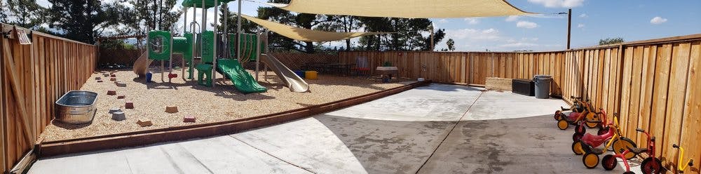 Outdoor playground with sand area, play structure, and shade sails