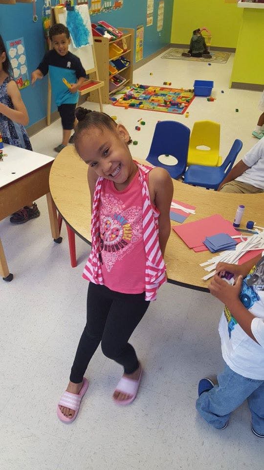 Child smiling in a classroom with other children