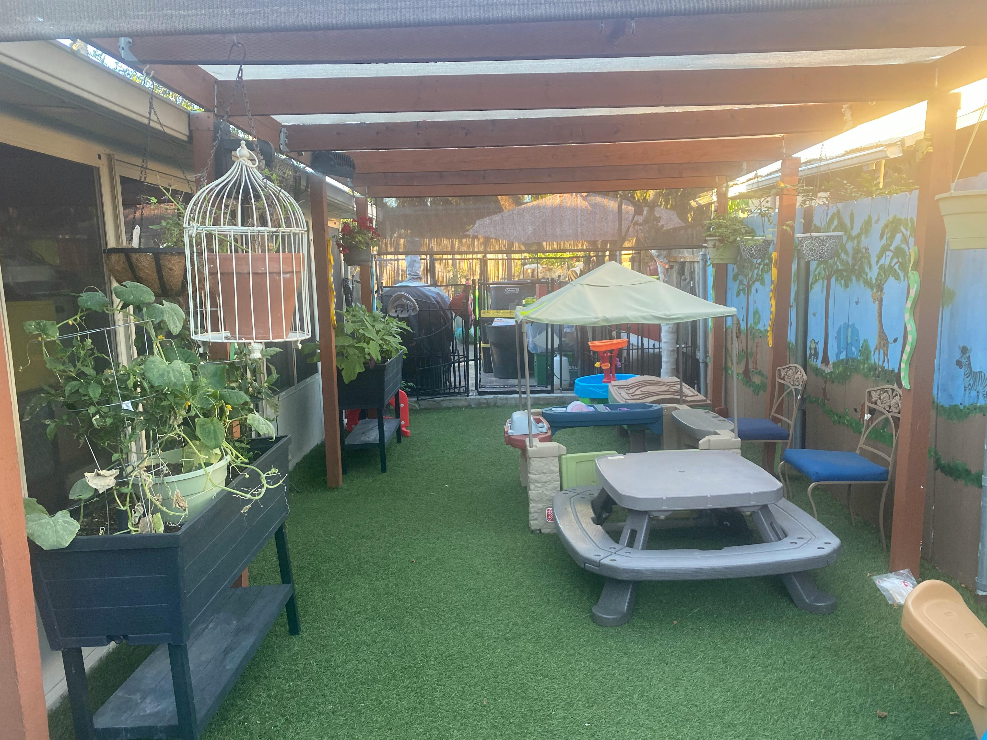 Outdoor patio with artificial turf, a small picnic table, and potted plants