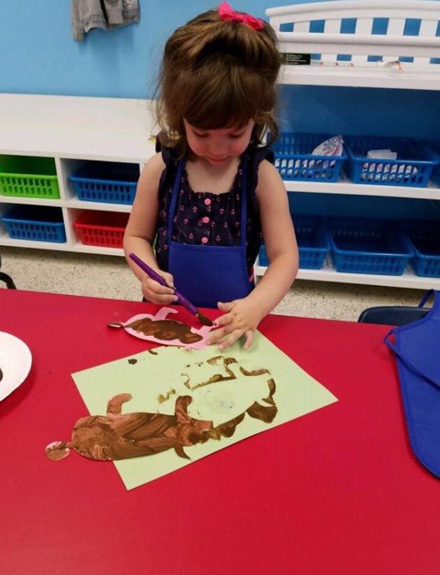 Child painting a cutout shape on paper