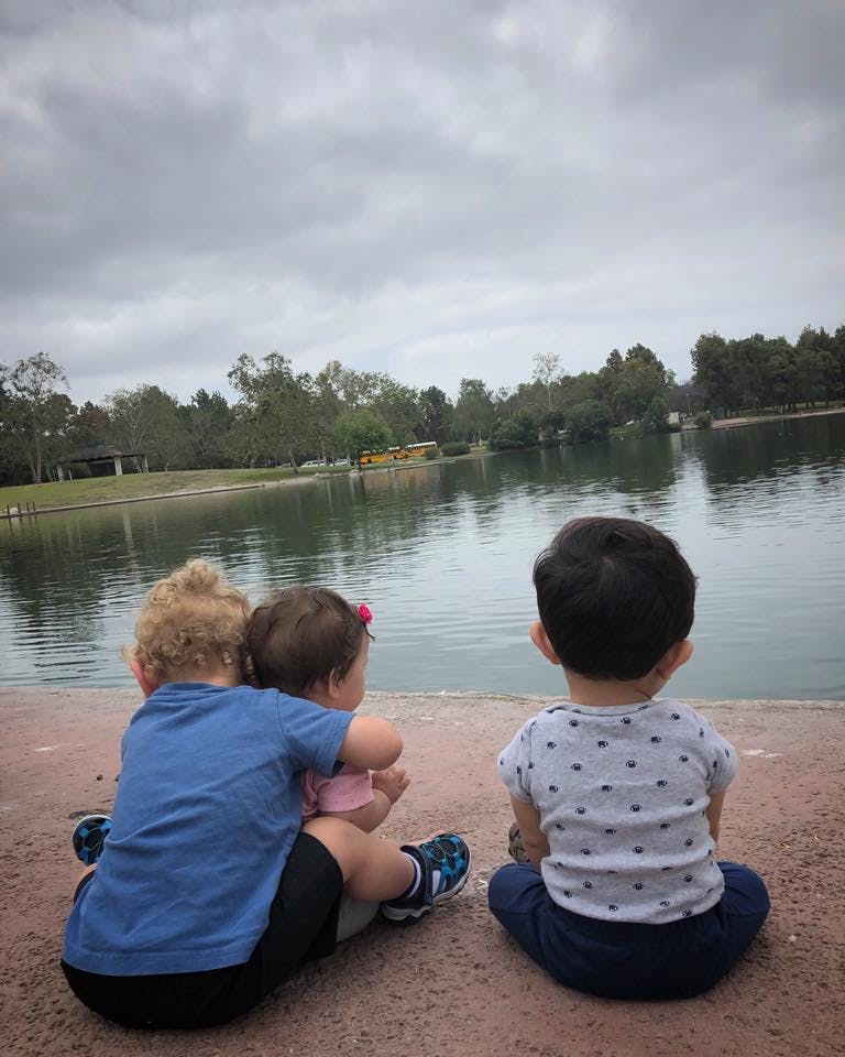 Three children sitting by a lake