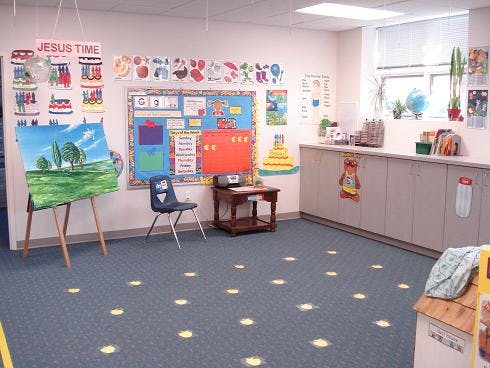 Empty classroom with bulletin boards, easel, and cabinets