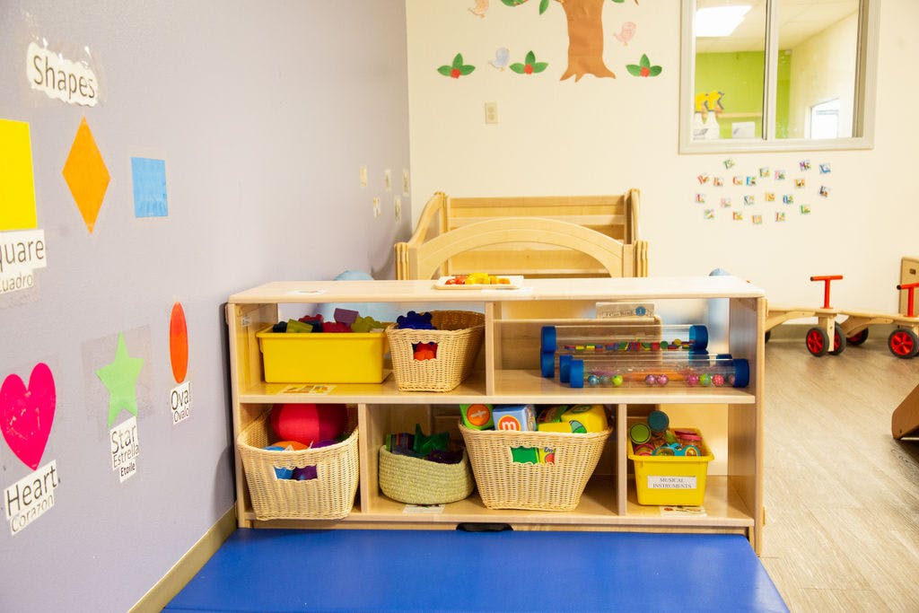 Classroom with shelves of toys, shape cutouts, and a small bed