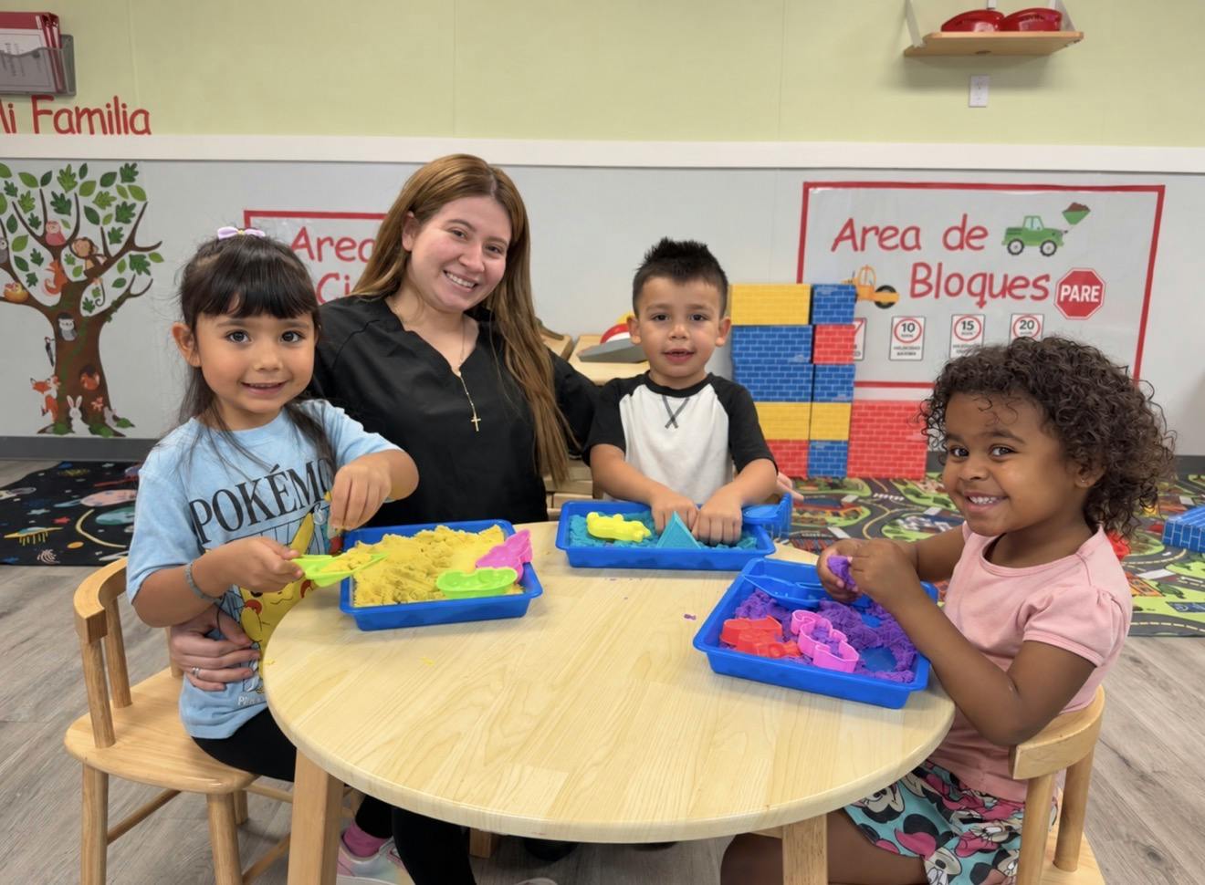 Adult and three children playing with modeling sand in a classroom