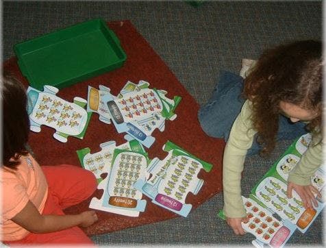 Two children playing with puzzle pieces on the floor