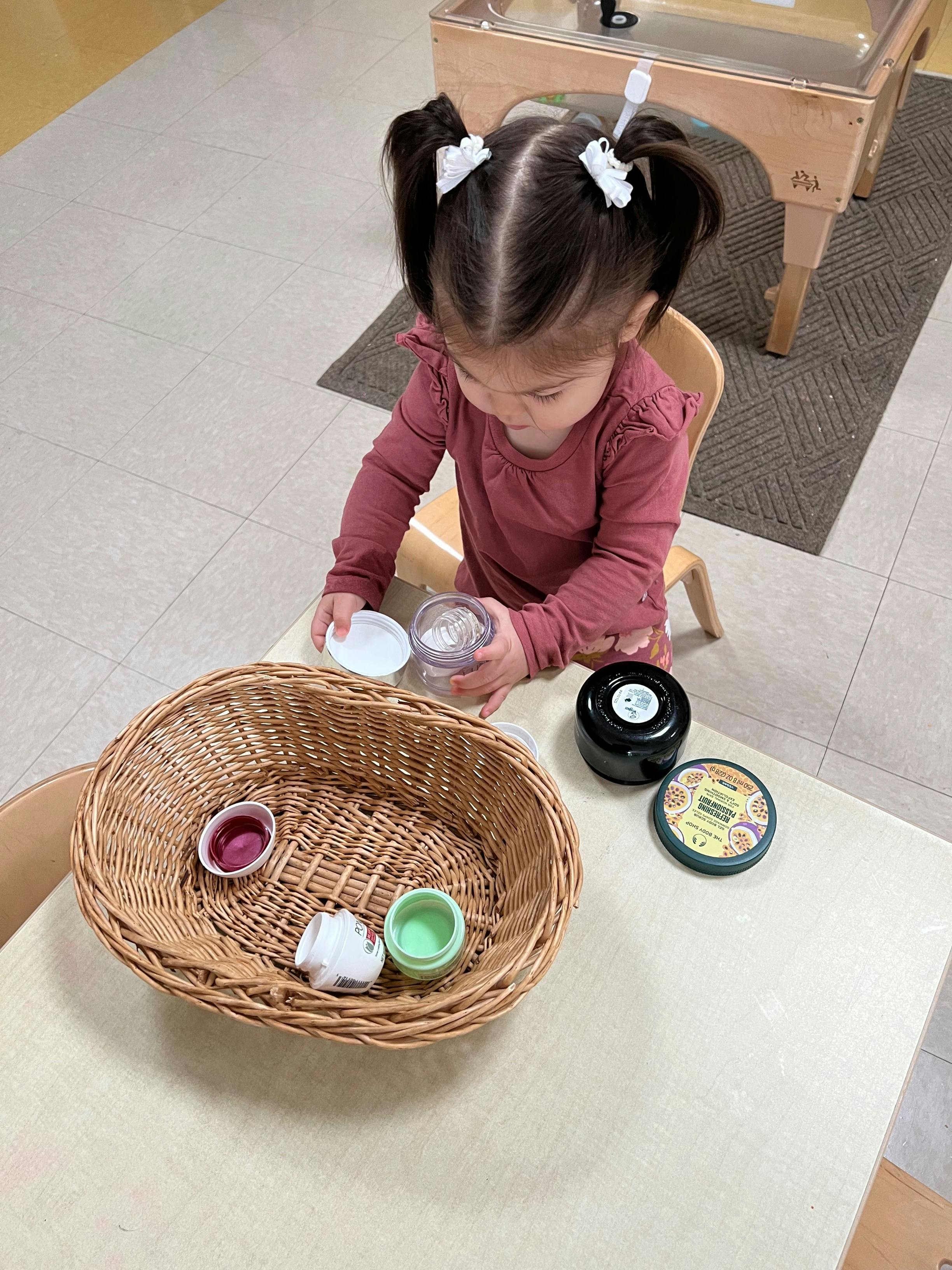 Child sitting at a table with a basket and small containers