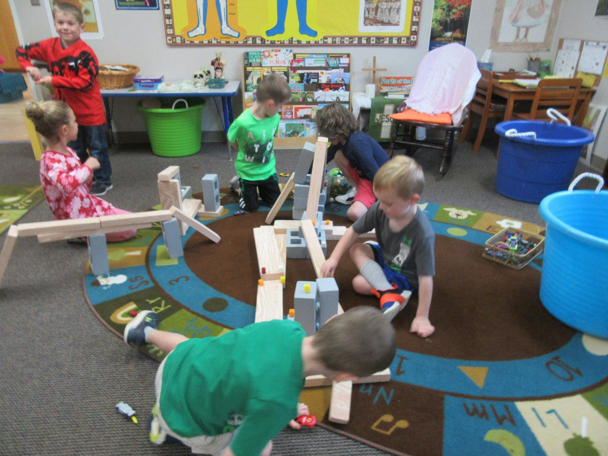 Children playing with wooden blocks on a rug in a classroom
