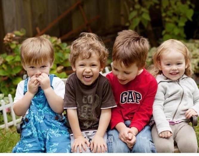Four young children sitting together outdoors