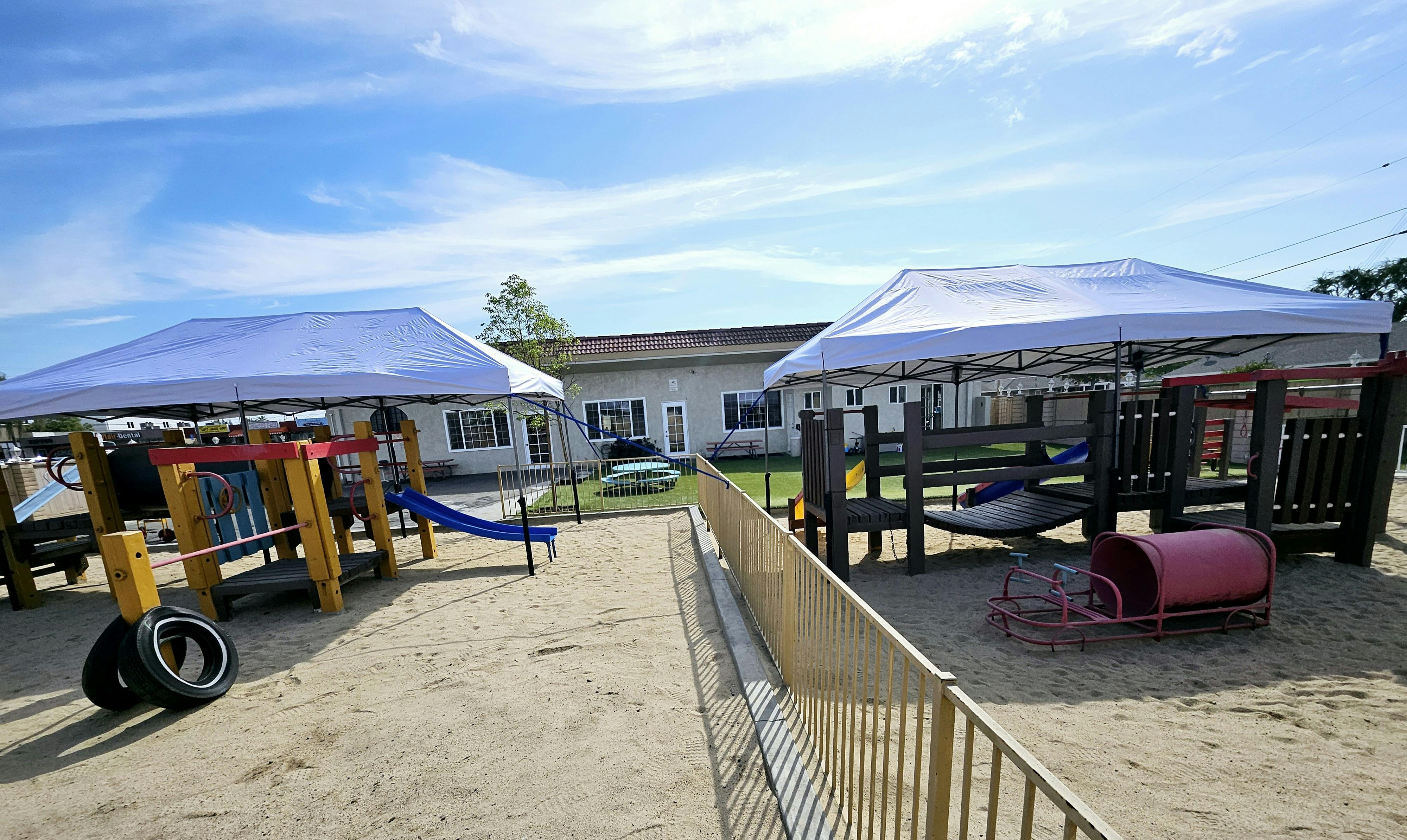 Playground with two white canopies over play structures