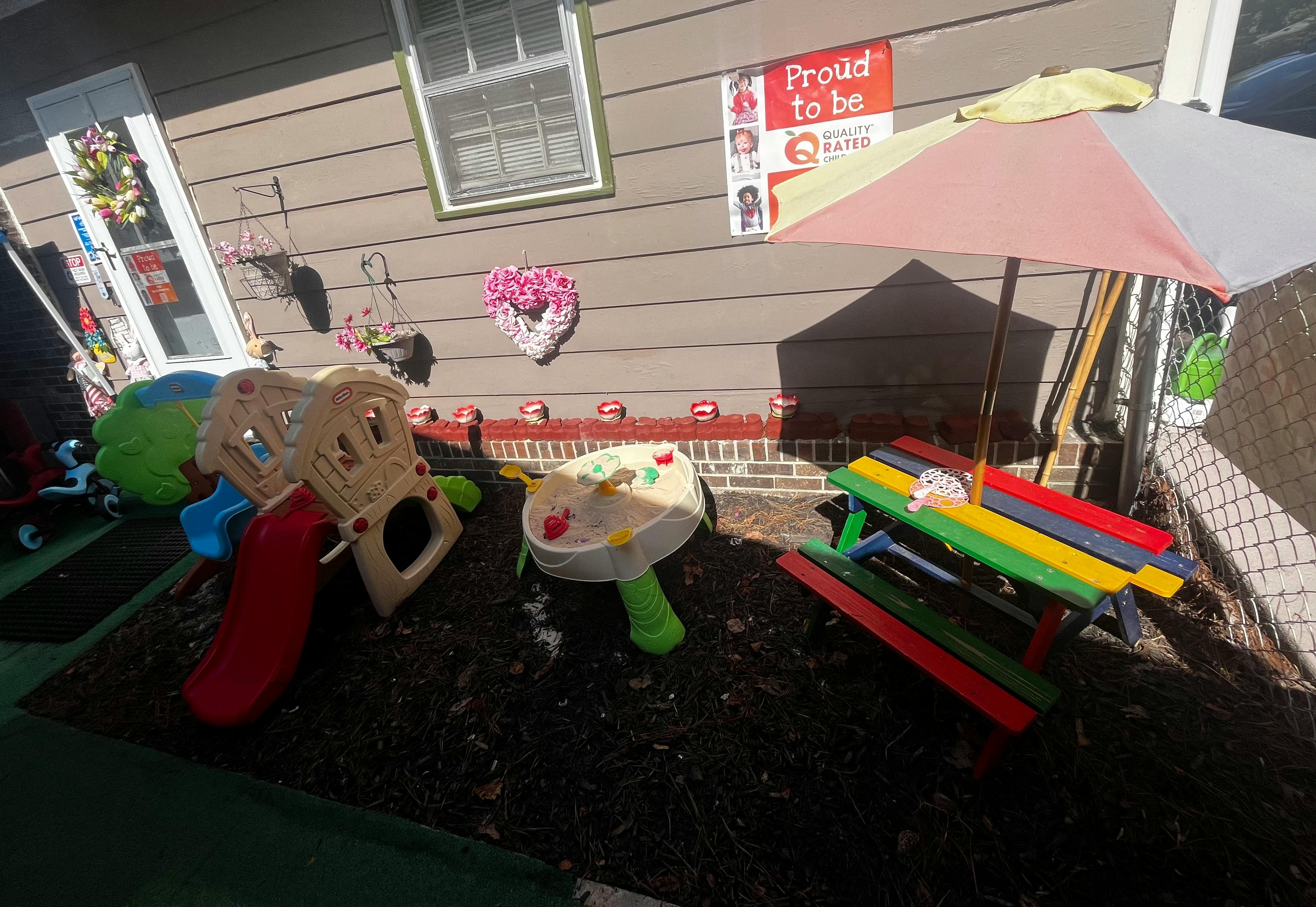 Children's play area with a slide, sand table, and colorful picnic table