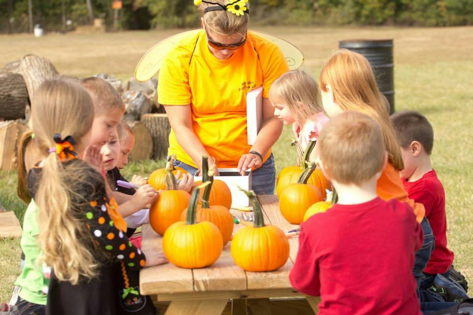 Adult and children gathered around a table with pumpkins
