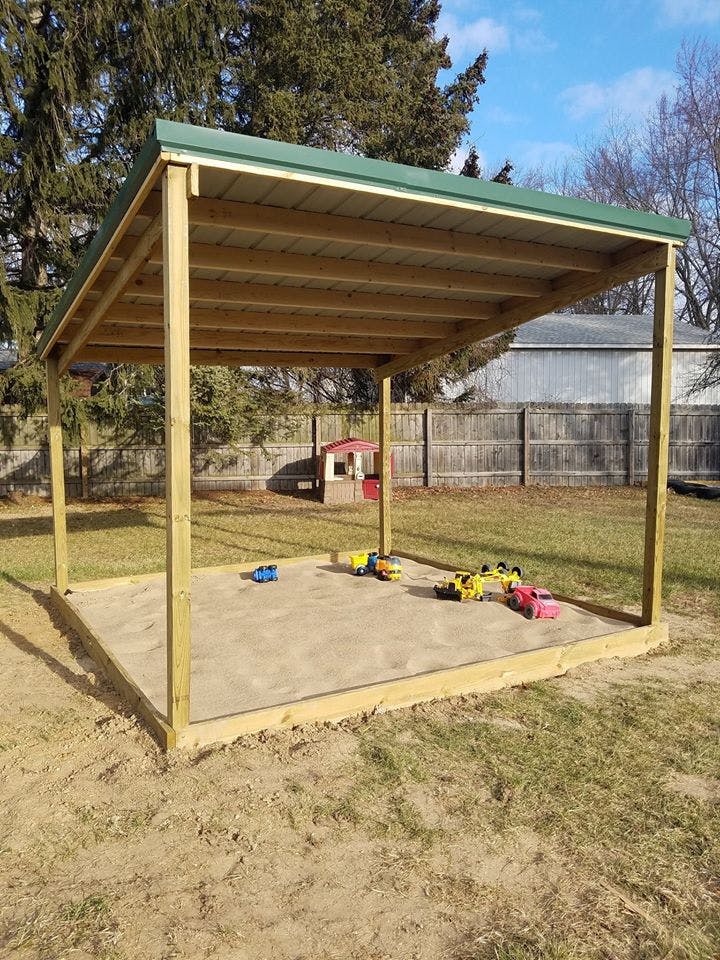 Covered sandbox with toy trucks inside