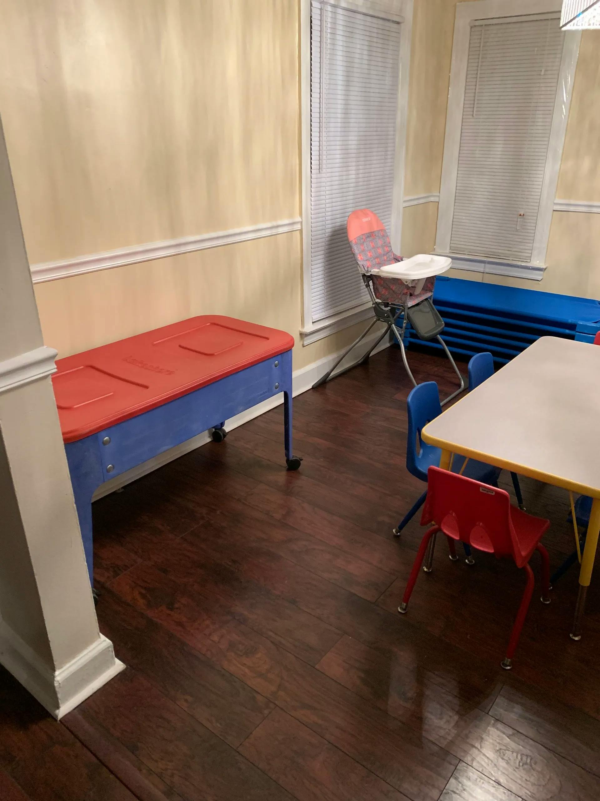 Children's play area with a red and blue table, high chair, and small table with chairs
