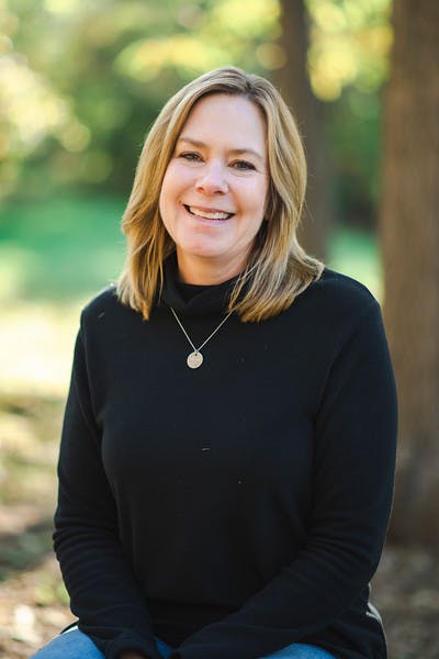 Person with long hair wearing a black turtleneck and necklace