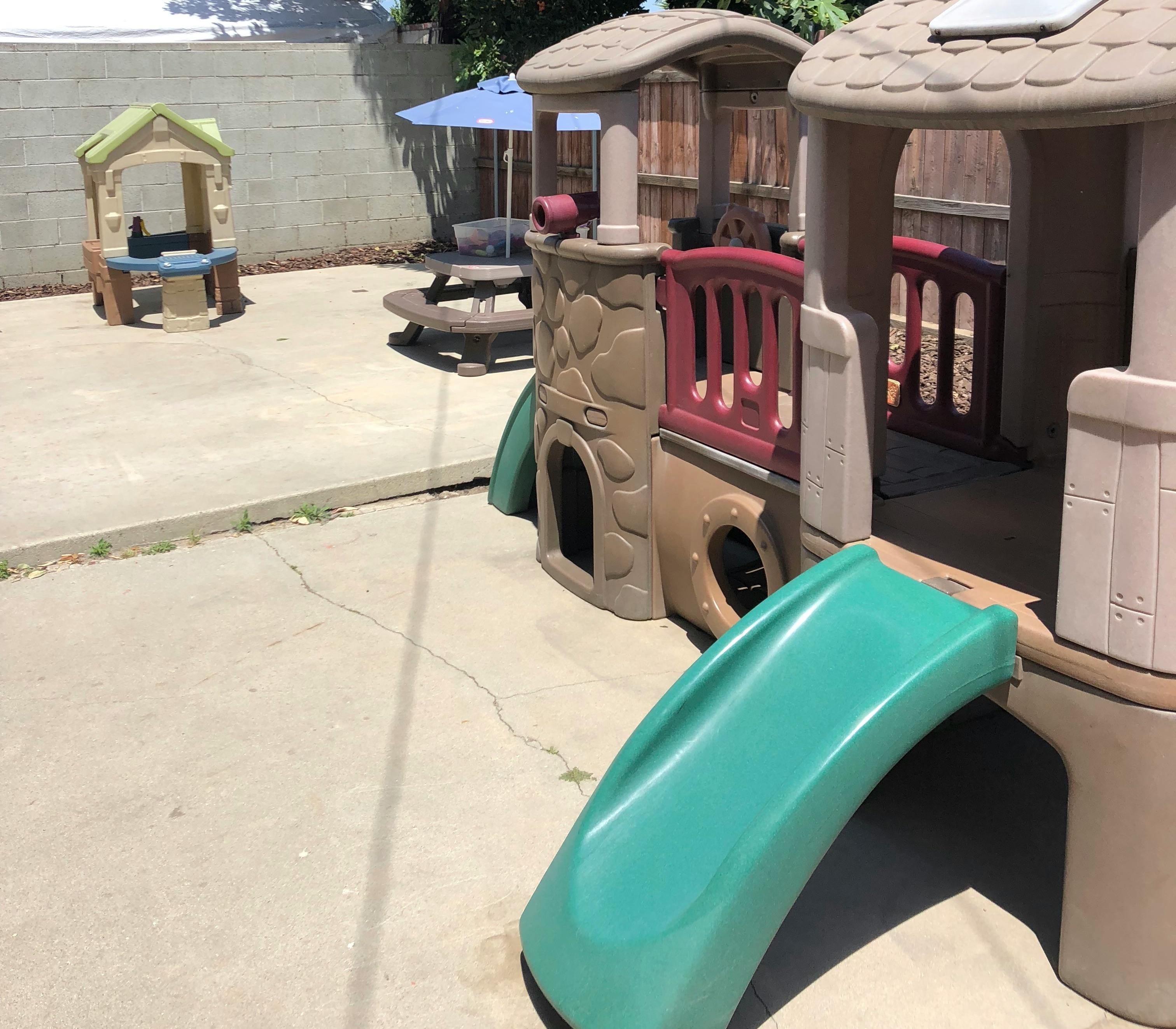 Play structure with slide and small playhouse on concrete