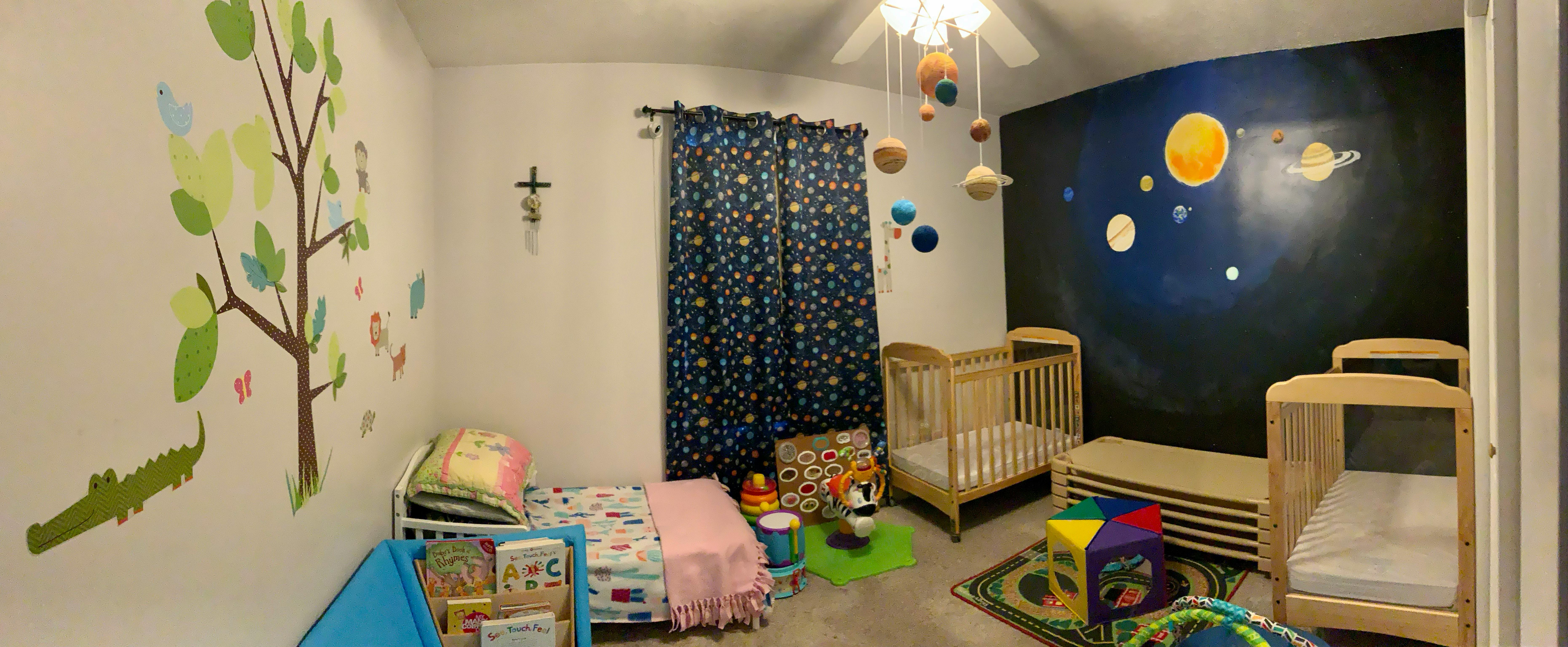 Children's room with two cribs, a bed, and a solar system mural