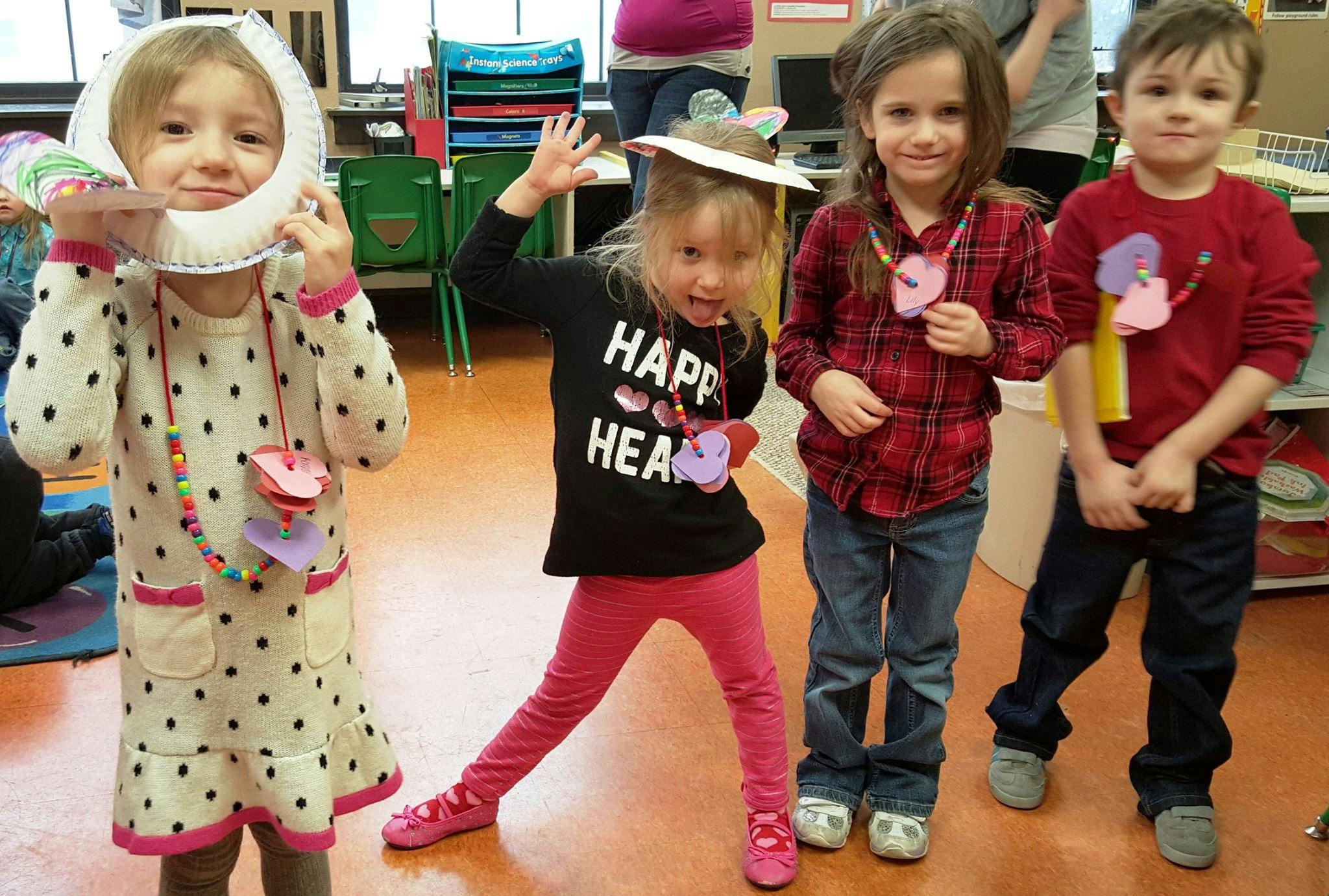Four children posing, one holding a paper plate frame to their face